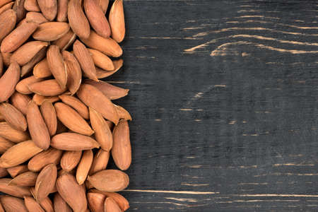 Scattered Uzbek almonds without the shell on an empty wooden background, top viewの写真素材