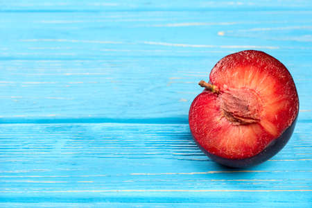 Half of juicy delicious red plums on an empty wooden backgroundの写真素材