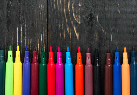 Open colored markers on wooden background top viewの写真素材