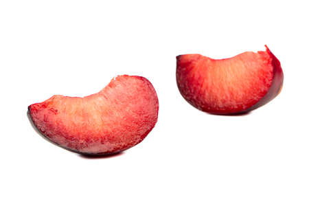 Two juicy slices of a red plum isolated on white backgroundの写真素材