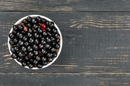 White bowl of bird cherries on an empty wooden background, top viewの写真素材