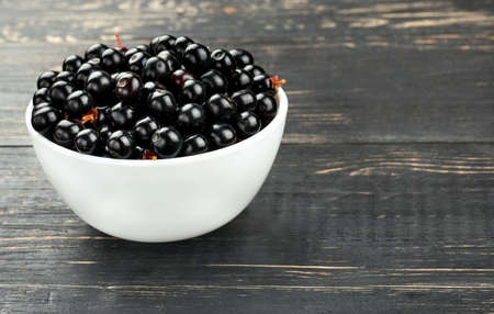 White bowl of bird cherries on a dark table closeupの写真素材