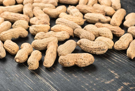 Scattered peanuts in the shell on wooden background, top view