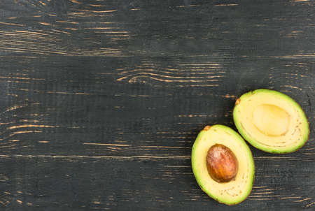 Two halves of the Hass avocado on an empty wooden background top view