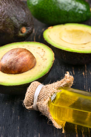 Avocado oil with halves of fruit on a close-up table