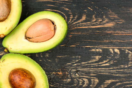 Halves of fresh avocado close-up on an empty wooden background