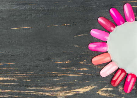 Palette of nail Polish on the empty wooden background, top view