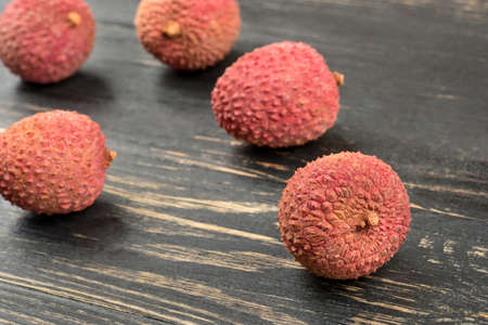Scattered fruit lychee in shell closeup on a dark tableの写真素材
