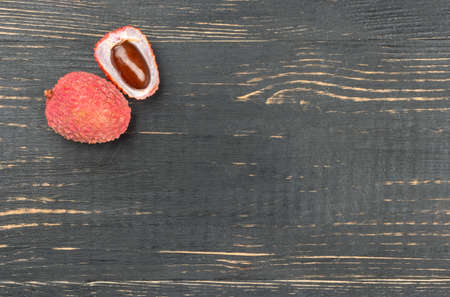 Ripe lychee fruit in-shell half on an empty wooden backgroundの写真素材