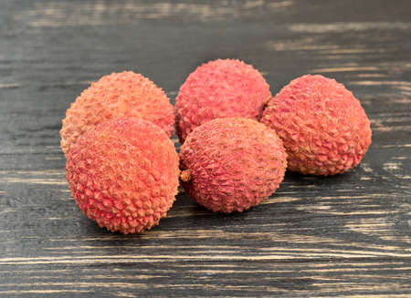 Several litchi fruits in shell on a wooden backgroundの写真素材