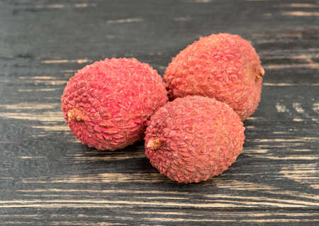 Three chinese lychee fruit closeup on a dark tableの写真素材