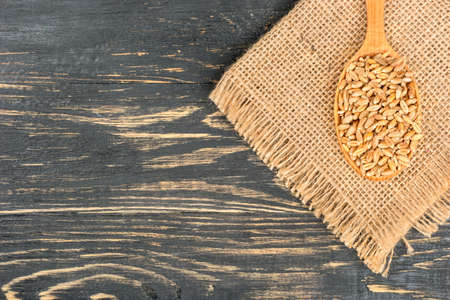 Wheat grain with spoon on burlap and empty wooden background, top viewの写真素材