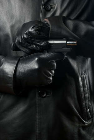Bandit in black clothes and gloves reloads the gunの写真素材
