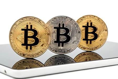 Gold and silver bitcoin coin on tablet close up