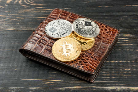 Gold and silver coins bitcoin on a leather purse on the tableの写真素材