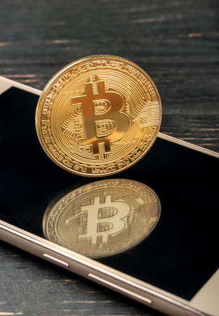 Bitcoin gold coin on smartphone close upの写真素材