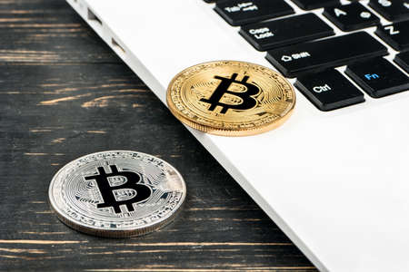 Gold and silver coin bitcoin on laptop closeup on tableの写真素材