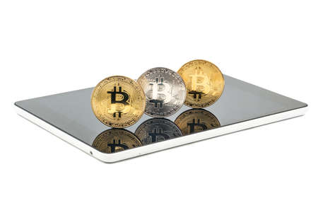 Three coins bitcoin on the tablet on a white backgroundの写真素材