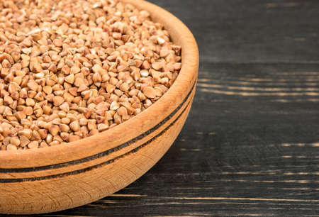 Part of the bowl with raw buckwheat on a dark table close-upの写真素材