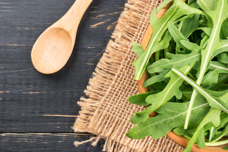 Fresh arugula in a bowl with a spoon on the table, top viewの写真素材