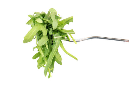 Fresh arugula leaves on a fork against white background