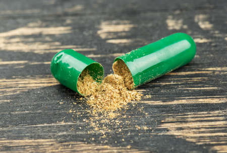Open green herbal capsule on table close upの写真素材