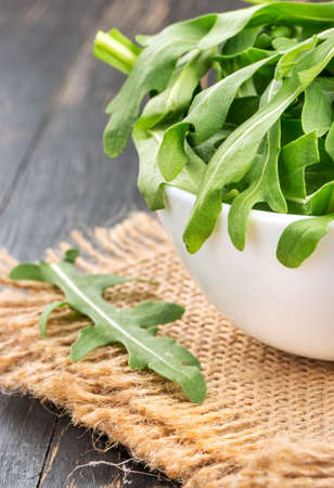 Leaves of fresh arugula in a bowl on burlap closeupの写真素材