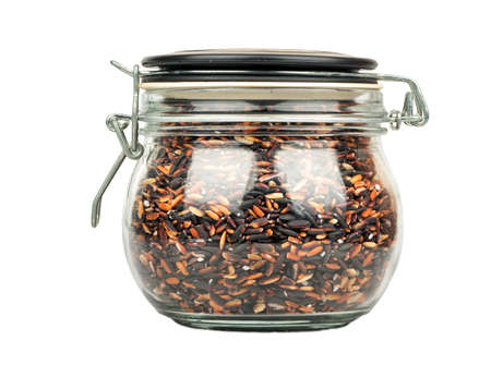 Black wild rice in glass jar on white backgroundの写真素材