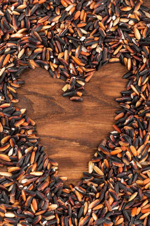 Black wild rice in heart shape on wooden backgroundの写真素材