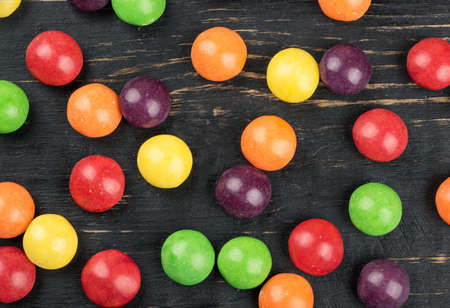 Scattered colorful candies on wooden background, top view