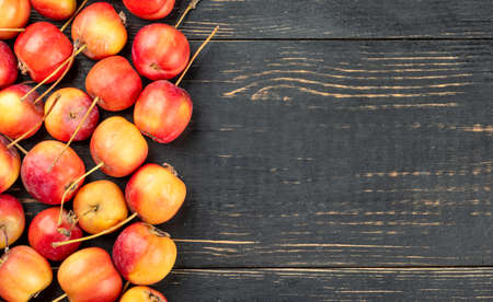 Scattered fresh paradise apples on empty wooden background, top view