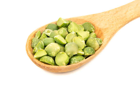 Small wooden spoon with dry green peas on white background closeup