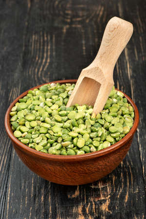 Dry green peas with a scoop in a bowl on the table