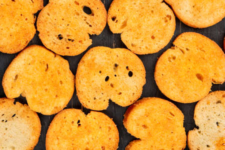 Scattered cracker bruschetta on wooden background closeup top view