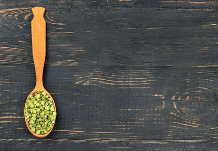 Dry green peas in a spoon on an empty wooden background, top viewの写真素材