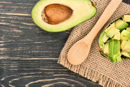 Salad with avocado with a spoon on sackcloth and table, top viewの写真素材