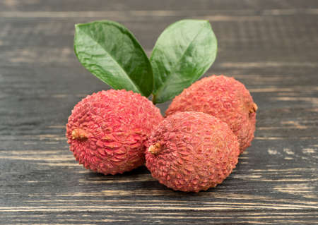 Three chinese lychee fruit with listen closeup on wooden backgroundの写真素材