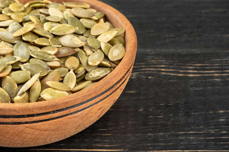 Part of a bowl of pumpkin seeds without a shell on the table