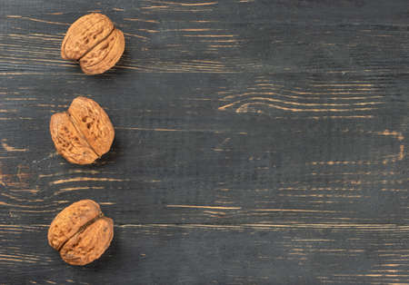 Three dry walnuts on an empty wooden background, top viewの写真素材