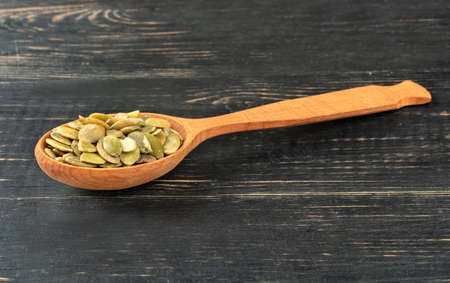 Pumpkin seeds without shell in spoon on wooden backgroundの写真素材