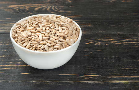 White bowl with sunflower seeds without shell on the tableの写真素材