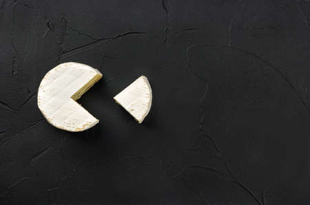Brie cheese with slice on dark concrete background, top viewの写真素材