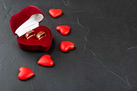 Two wedding rings with red box and hearts on concrete backgroundの写真素材