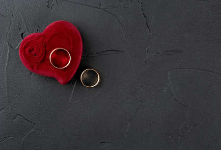 Two wedding rings with red box on dark background, top viewの写真素材