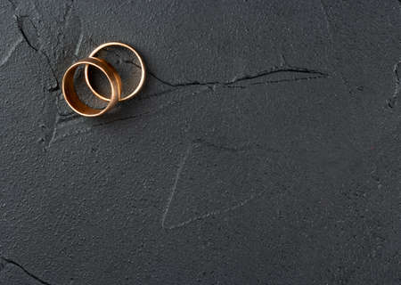 Two wedding rings on an empty dark concrete background, top viewの写真素材