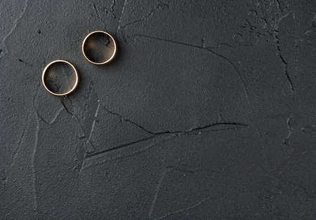 Two wedding rings on an empty dark concrete background, top viewの写真素材