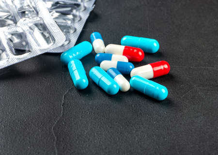 Scattered multicolored capsules with blister on a dark backgroundの写真素材