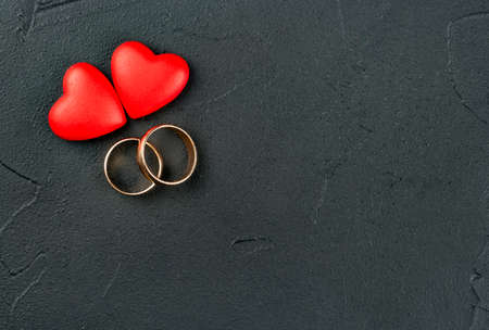 Gold engagement rings with two hearts on dark background, top viewの写真素材