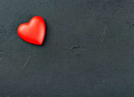 One red plastic heart on an empty concrete background, top viewの写真素材
