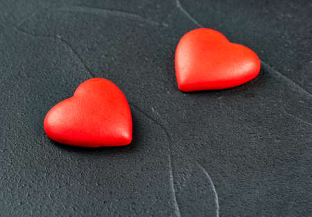 Two plastic hearts symbolizing Valentine's day on a dark backgroundの写真素材